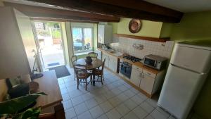 a kitchen with a table and a refrigerator at Gîte LA COUMERETTE in Les Hautes-Rivières