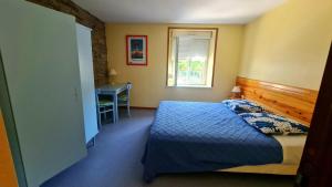 a bedroom with a bed and a desk and a window at Gîte LA COUMERETTE in Les Hautes-Rivières