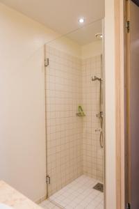 a bathroom with a shower with white tiles at Kuressaare Marina Apartment in Kuressaare