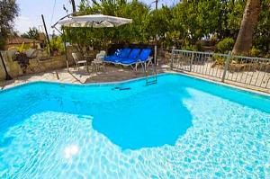 una gran piscina azul con sillas y sombrilla en Rose Garden Villa Peristerona, en Peristerona