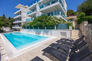 a swimming pool with chairs and a building at Villa Aqua in Zaboric