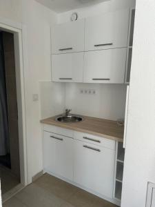 a kitchen with white cabinets and a sink at Sarajevo-Hotonj Apartman in Sarajevo