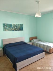 Un dormitorio con dos camas y una pared azul. en De Gama 2, en Marina di Ragusa