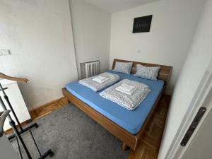 a small room with a bed with blue sheets and pillows at Sarajevo-Hotonj Apartman in Sarajevo