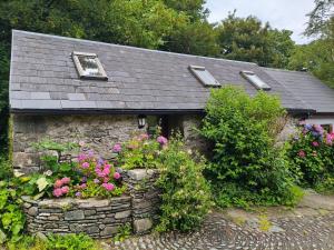 a small stone house with flowers in front of it at An Cábáin Cúlú in Killarney
