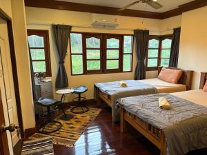 a bedroom with two beds and a table and windows at Sweet home in Bangrak Beach