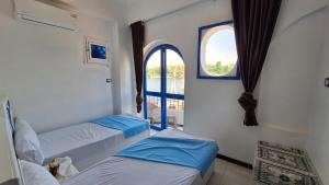 two beds in a room with a window at NOBATiA Guest House 2 in Aswan +14 photos