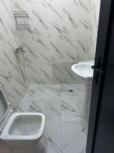a white bathroom with a toilet and a sink at barbare in Gonio