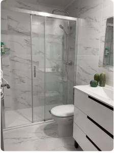 Un baño blanco con ducha y WC. en Cómodo y tranquilo a 2 minutos del metro, en Madrid