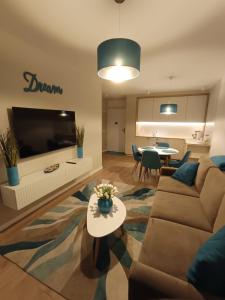 a living room with a couch and a table at Apartament Whiteblue Dream 2 Kołobrzeg z ogródkiem & sauna & fitness & bawialnia dla dzieci in Kołobrzeg