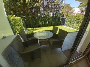 a patio with a glass table and chairs on a balcony at Apartament Whiteblue Dream 2 Kołobrzeg z ogródkiem & sauna & fitness & bawialnia dla dzieci in Kołobrzeg