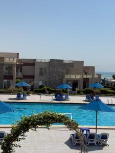 a swimming pool with chairs and umbrellas at Elite residence ain elsokna in Ain Sokhna +1 photo