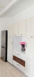 a kitchen with white cabinets and a vase with pink flowers at TORRE LAPILLO Fronte Mare in Centro con parcheggio coperto in Torre Lapillo