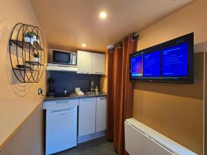 una piccola cucina con una grande TV a schermo piatto sul muro di 1G- Studio tout equipé proche de la scène musicale a Issy-les-Moulineaux