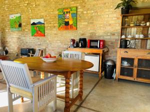 a kitchen with a wooden table and white chairs at Apple Cottage in Grabouw