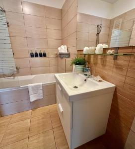 a bathroom with a white sink and a bath tub at Remora Apartman Balatonszemes in Balatonszemes +17 photos