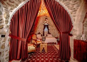 een kamer met rode gordijnen en een tafel en stoelen bij Ali paşa konağı mardin in Mardin