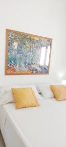 a painting above a white bed with yellow pillows at TORRE LAPILLO Fronte Mare in Centro con parcheggio coperto in Torre Lapillo