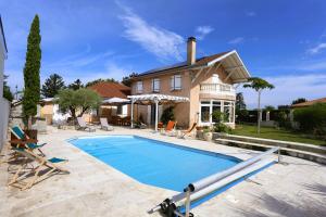 a swimming pool in front of a house at Les chambres de la Dombes in Pizay