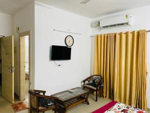 a living room with a clock on the wall and a tv at HMStay Vrindavan in Vrindāvan