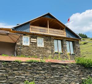 una antigua casa de piedra con un muro de piedra en Guest House MARGALITI-საოჯახო სასტუმრო მარგალიტი, en Omalo