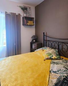 a bedroom with a bed with a yellow blanket at La Maison des Oiseaux in Crouzilles