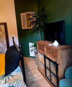 a living room with a television on a wooden dresser at La Maison des Oiseaux in Crouzilles