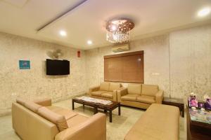 バンガロールにあるHotel Amshi Internationalのソファ、テーブル、テレビが備わる待合室