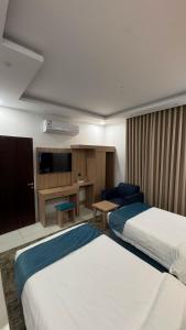 a hotel room with two beds and a television at جود المدينة للإجنحة الفاخرة in Medina