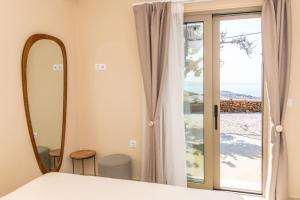 ein Schlafzimmer mit einem Bett, einem Spiegel und einem Fenster in der Unterkunft Horizon Hill Villa in Tinos + 38 Fotos