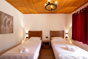 two beds in a room with red curtains at Old Street Villa in Gjirokastër