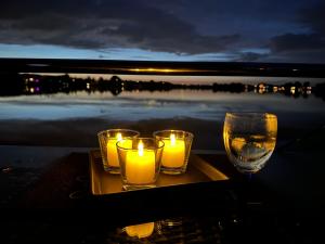 MaasbommelHausboot KOMET Luxus und Natur pur max 5 Pers的托盘里放着三根蜡烛和一杯水