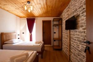 a bedroom with two beds and a brick wall at Old Street Villa in Gjirokastër +22 photos