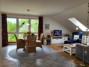 un salon avec une table, des chaises et une télévision dans l'établissement Ferienwohnung Am Sommerdeich, à Sankt Peter-Ording