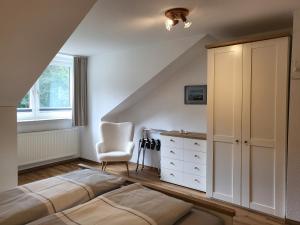 - une chambre mansardée avec 2 lits et une chaise dans l'établissement Ferienwohnung Am Sommerdeich, à Sankt Peter-Ording