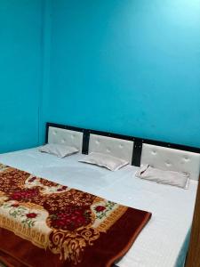 a bed in a room with a blue wall at Ramashrya Homestay Peaceful Stay Near Mahakal & Railway Station in Ujjain