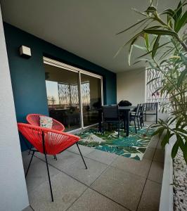 a living room with a red chair and a table at Les terrasses du port in Canet-en-Roussillon