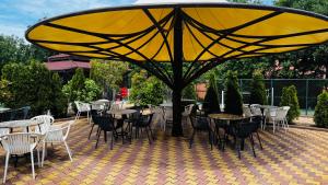 a large yellow umbrella on a patio with tables and chairs at Hotel Neva in Kiten