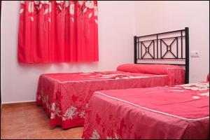 コニル・デ・ラ・フロンテーラにあるChalet Pinar de Roche 118の赤いシーツと窓が備わるベッド2台付きの客室です。