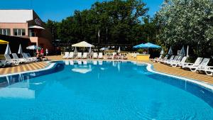 ein großer blauer Swimmingpool mit Stühlen und Sonnenschirmen in der Unterkunft Hotel Neva in Kiten