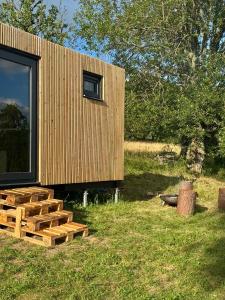 a small wooden house with a pile of logs at Jeseníky glamp in Dolní Moravice +6 photos