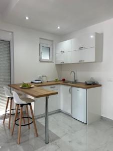 a kitchen with white cabinets and a wooden table at Apart Hotel White Pearl in Bar