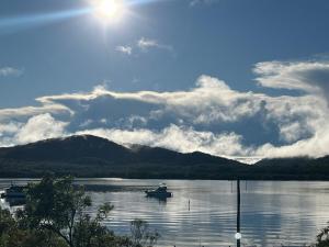 a boat on a lake with mountains in the background at Riverside Retreat in Karuah