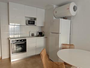 a white kitchen with a table and a white refrigerator at Apartamento Portonovo-Baltar in Portonovo