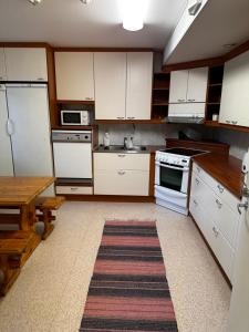 a kitchen with white cabinets and a table and a rug at Himangan majatalo in Kalajoki