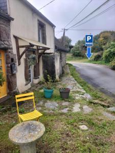 a yellow chair sitting next to a building next to a street at "La Maison de Poupée" Gîte cosy Monts d'Arrée proche Huelgoat Bretagne in Berrien