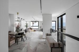 a white living room with a table and chairs at ריזורט האחוזה- וילה עם בריכה פרטית וסוויטות עם בריכה משותפת מול נוף ים המלח in Neve Zohar