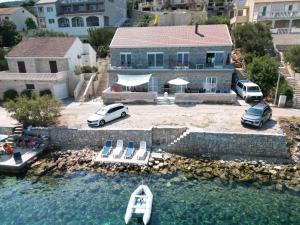 a house with chairs and a boat in the water at Apartmani Katarina in Pupnat