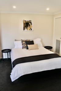 een slaapkamer met een groot wit bed met kussens bij The Commercial Hotel Wallerawang in Wallerawang