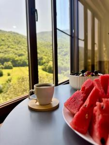 a table with a plate of watermelon and a cup of coffee at Goshniver Rest House in Dilijan +8 photos